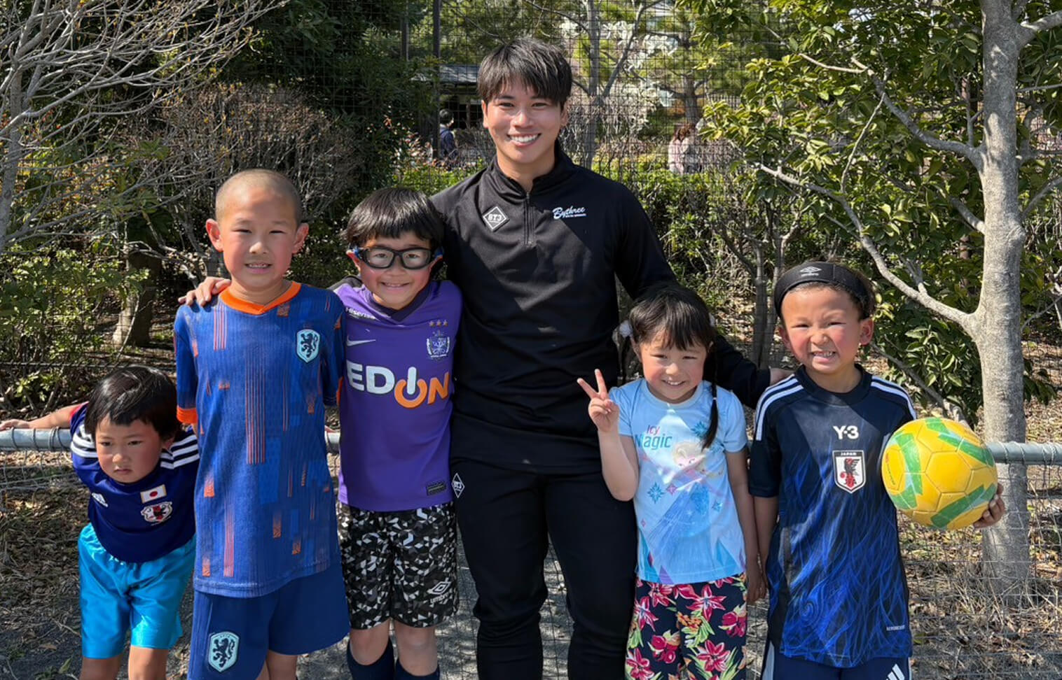 子供たちとコーチが肩を組んで並んでいる